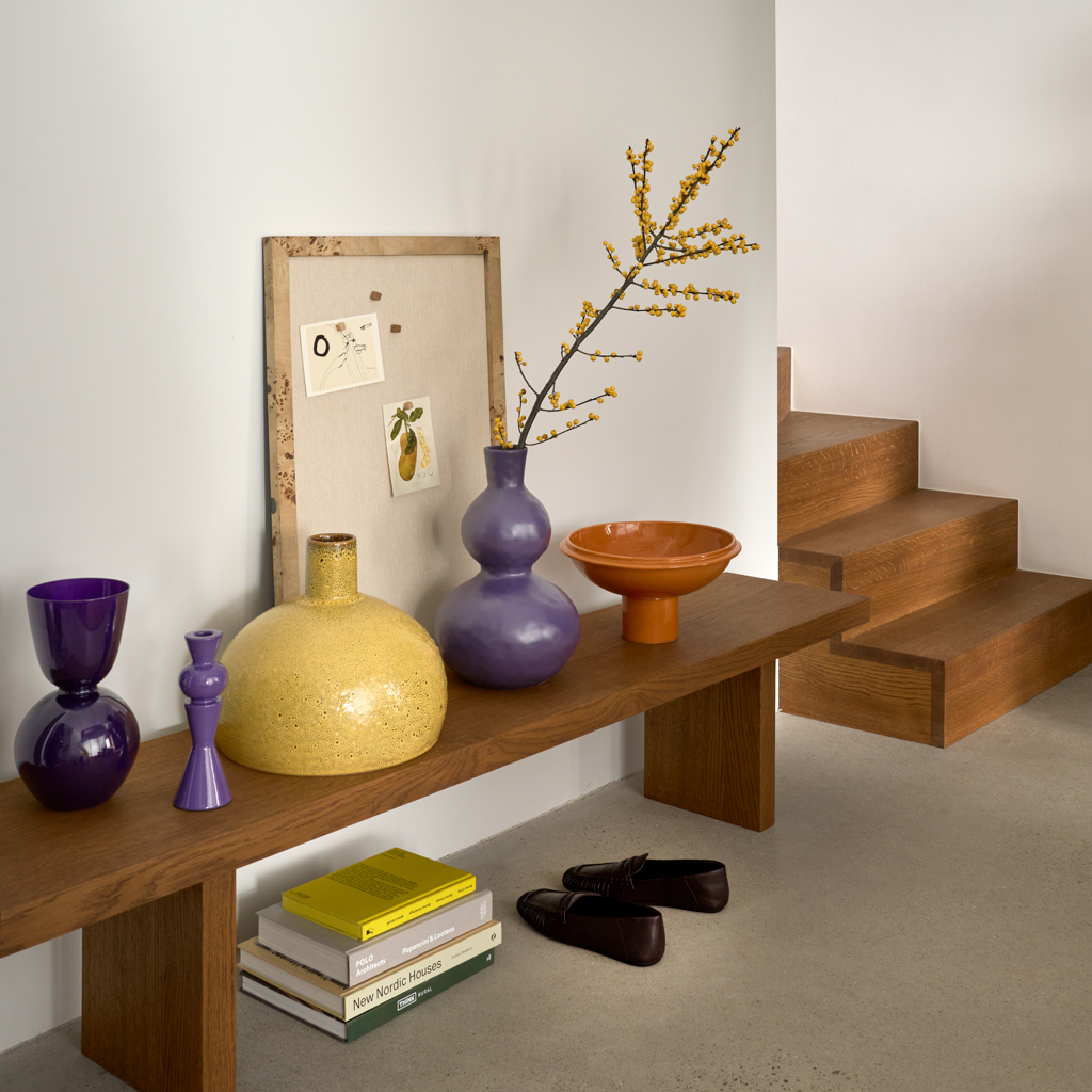 A big bold, flattened round ceramic vase with a small straight neck, featuring an artful shiny reactive glaze in the rich mustard like colour. Statement piece.