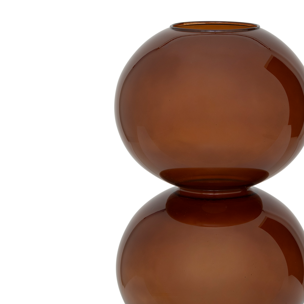 A large recycled glass vase with two layered spherical forms, balanced in the inviting and warm sugar almond colour. Transparant coloured.