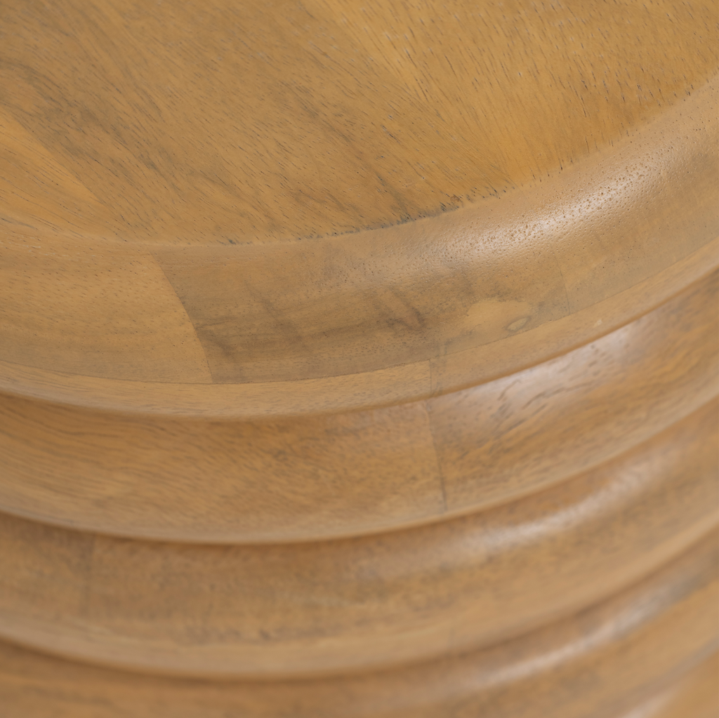 A layered, bulky round solid wood side table with four sturdy legs, in a shiny light oak finish that gives the table an urban look. Made of eco-friendly mangowood, of which the timber is harvested after the mango tree passed its fruit-bearing life span.