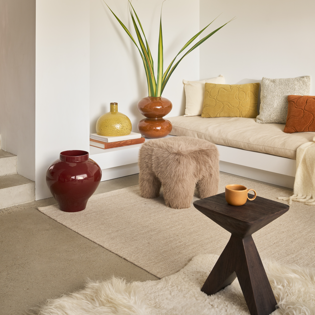 A sturdy pouf with rounded, chunky legs and a soft long hair furry weave in colour taupe.