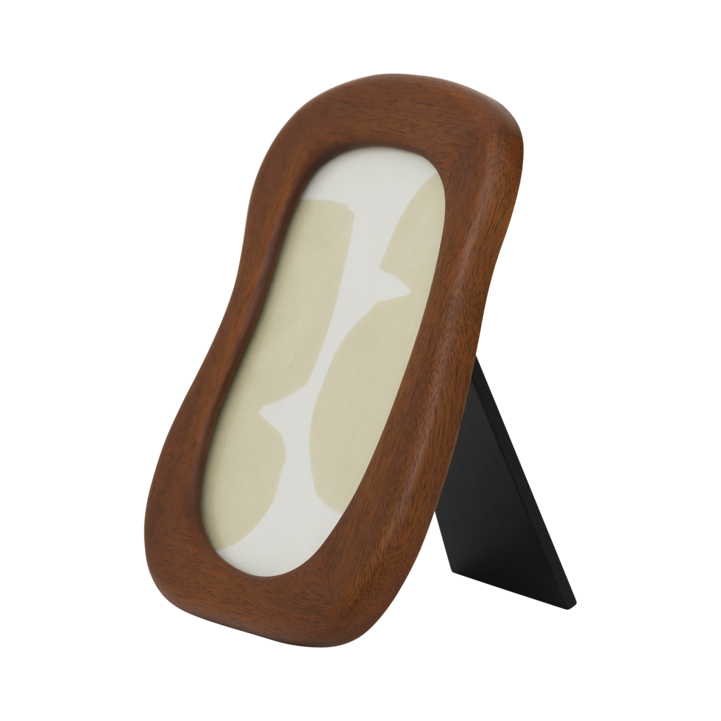 A photo frame with stand in an organic, flowing design finished in a warm golden oak colour. Made of eco-friendly mangowood, of which the timber is harvested after the mango tree passed its fruit-bearing life span.