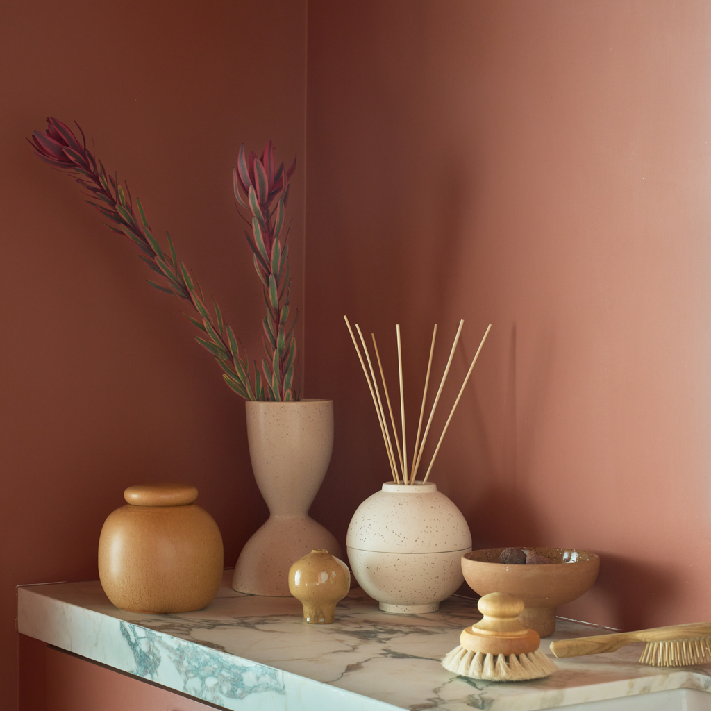 A spherical fragrance holder in off-white with a subtle textured skin, designed to store your whole fragrance bottle with an opening for scented sticks.
